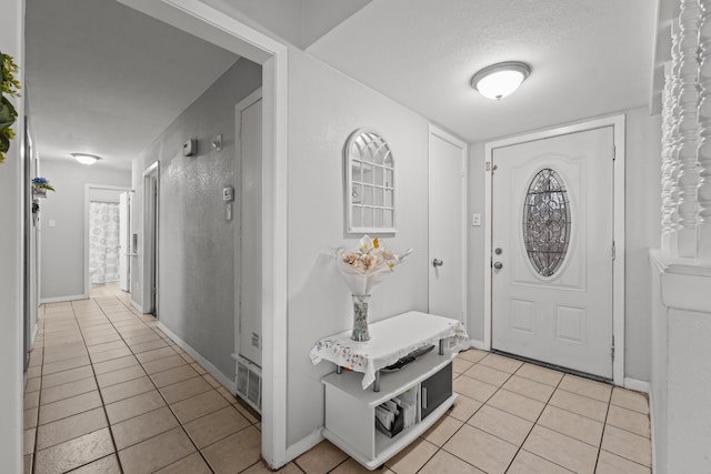 foyer featuring light tile patterned floors and a textured ceiling