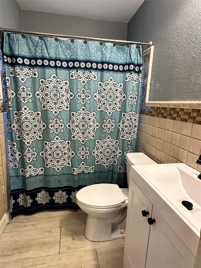 bathroom featuring tile walls, vanity, and toilet