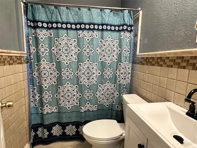 bathroom featuring vanity, toilet, and tile walls