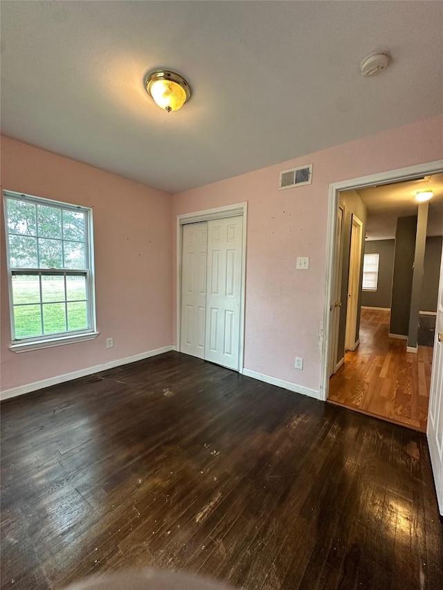 unfurnished bedroom with dark hardwood / wood-style floors and a closet