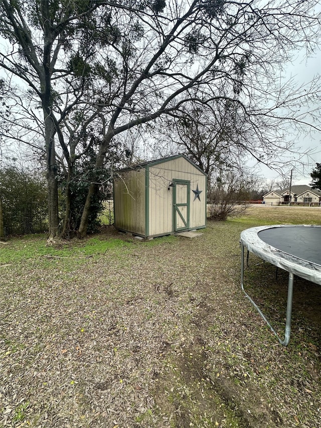 view of yard featuring a trampoline and a storage shed