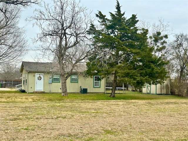 view of yard featuring central AC unit, a trampoline, and a shed