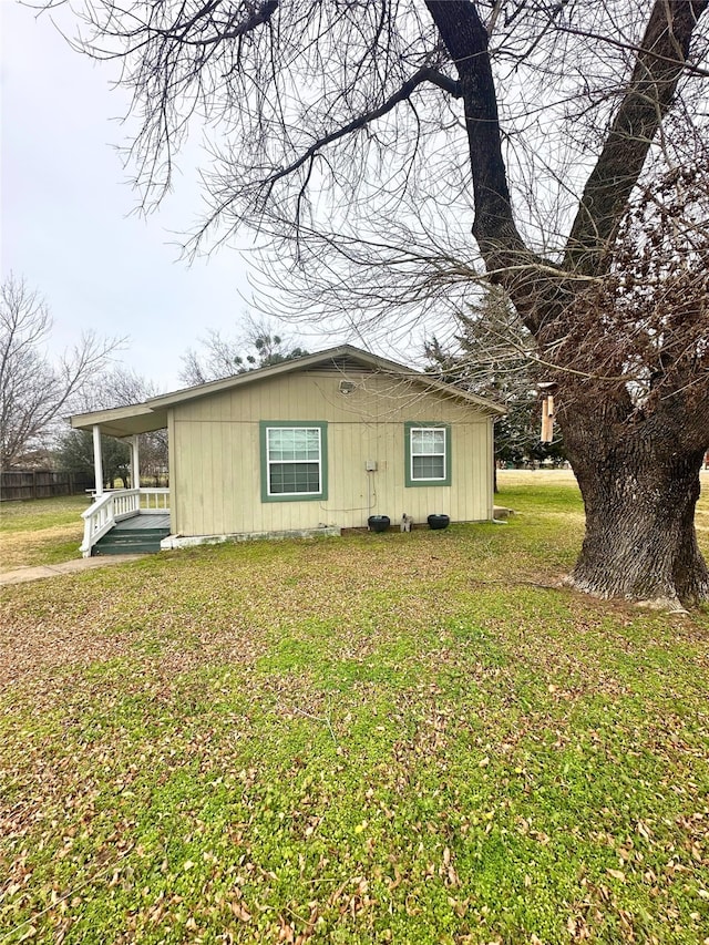 view of side of property featuring a yard and covered porch