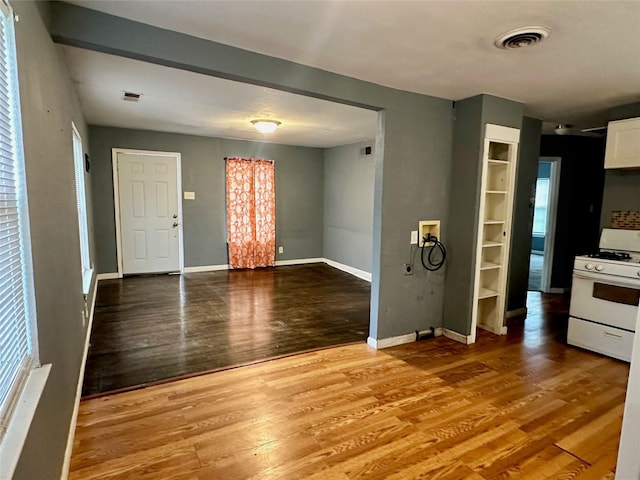 interior space with white cabinetry, white range with gas stovetop, and hardwood / wood-style flooring