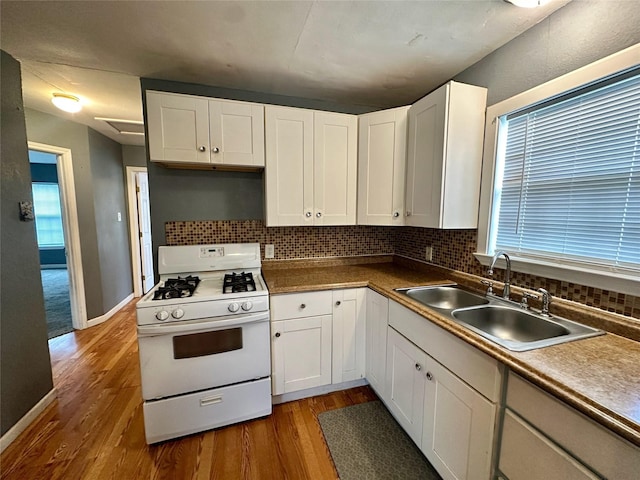 kitchen featuring white range with gas cooktop, sink, hardwood / wood-style floors, and white cabinets