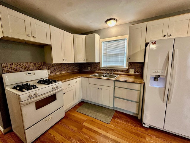 kitchen featuring white cabinetry, sink, white appliances, and light hardwood / wood-style flooring