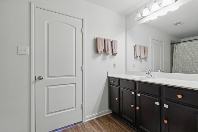 bathroom with vanity, wood finished floors, visible vents, and baseboards