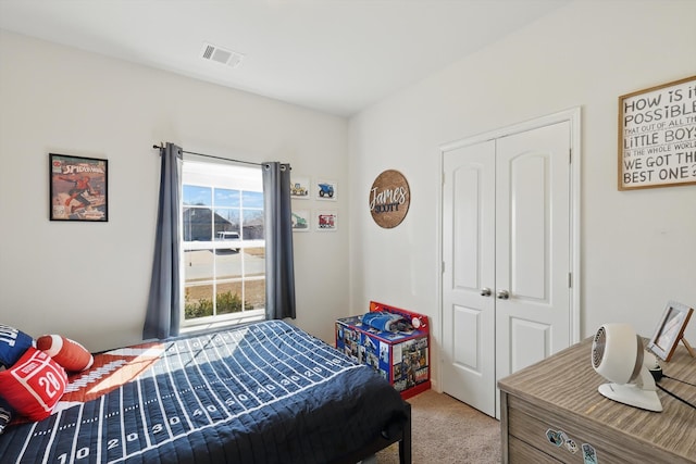 bedroom with a closet, visible vents, and light colored carpet