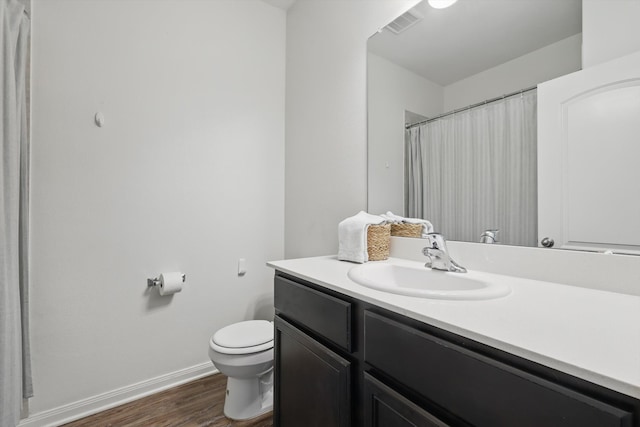 full bathroom with visible vents, toilet, vanity, wood finished floors, and baseboards