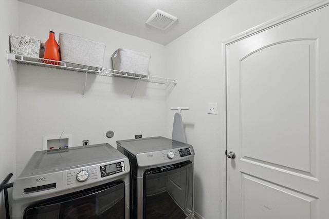 laundry area with laundry area, visible vents, and washer and clothes dryer