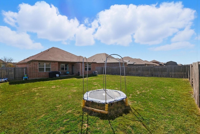 view of yard featuring a trampoline and a fenced backyard