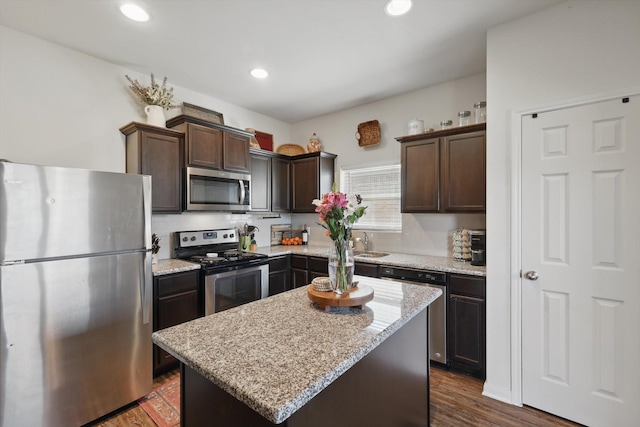 kitchen featuring stainless steel appliances, a center island, dark brown cabinets, and dark wood-style floors