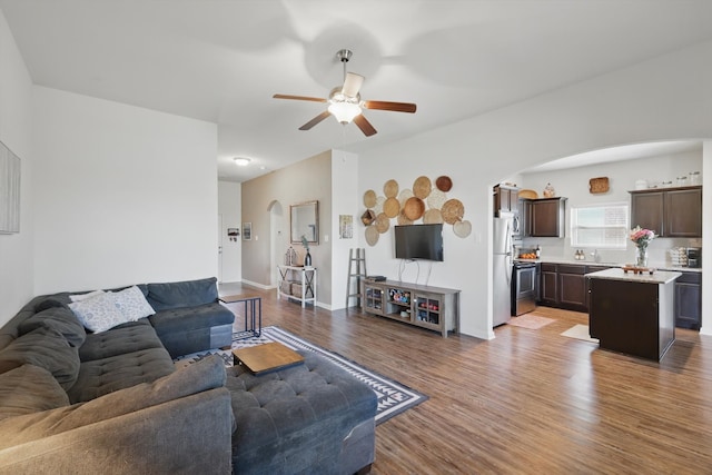 living room with arched walkways, ceiling fan, and wood finished floors