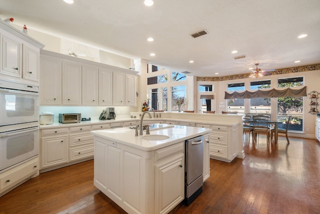 kitchen with dark hardwood / wood-style floors, kitchen peninsula, double oven, a kitchen island with sink, and white cabinets