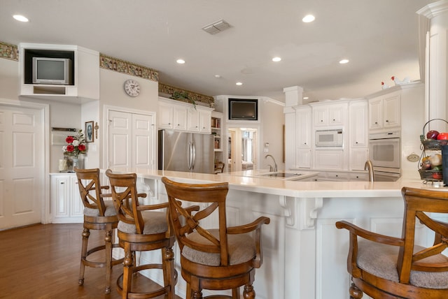 kitchen with sink, a breakfast bar area, white cabinets, kitchen peninsula, and white appliances