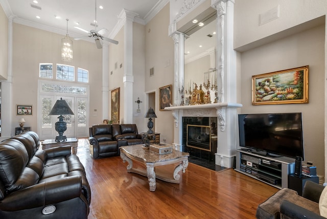 living room featuring a fireplace, decorative columns, hardwood / wood-style flooring, ornamental molding, and ceiling fan