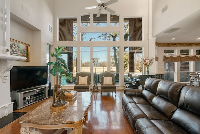 living room featuring ornate columns, a high ceiling, hardwood / wood-style floors, and ceiling fan