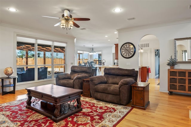 living room with crown molding, ceiling fan, sink, and light hardwood / wood-style flooring