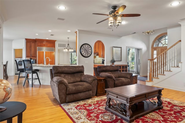 living room with ceiling fan with notable chandelier and light wood-type flooring