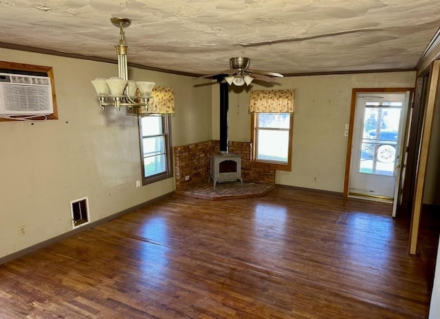 unfurnished living room with crown molding, dark hardwood / wood-style floors, a wall unit AC, and a wood stove