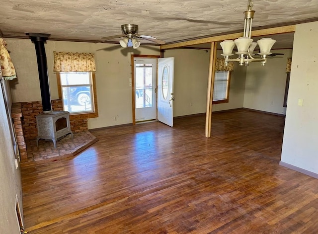 unfurnished living room featuring dark hardwood / wood-style flooring, ceiling fan with notable chandelier, and a wood stove