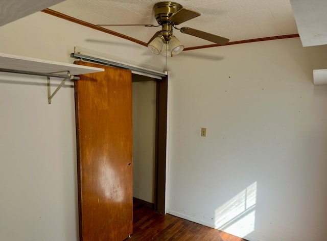 unfurnished bedroom featuring dark wood-type flooring, ceiling fan, ornamental molding, and a closet