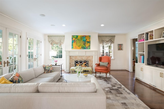 living room featuring dark hardwood / wood-style flooring, crown molding, a high end fireplace, and french doors