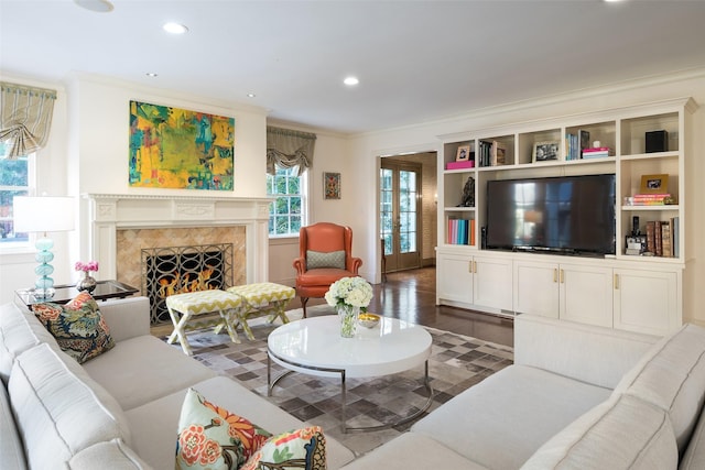 living room featuring dark wood-type flooring, ornamental molding, a premium fireplace, and french doors