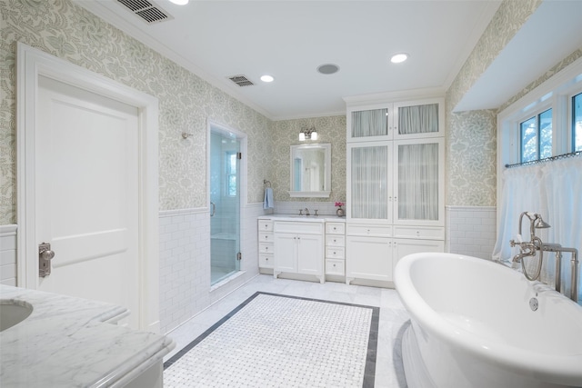 bathroom with vanity, ornamental molding, independent shower and bath, and tile walls