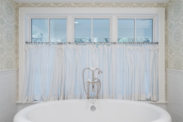 bathroom with a tub and tile walls