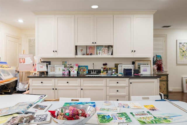 interior space with white cabinetry, sink, and dark stone counters