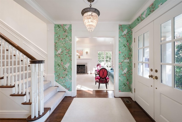 entrance foyer featuring an inviting chandelier, crown molding, dark wood-type flooring, and french doors