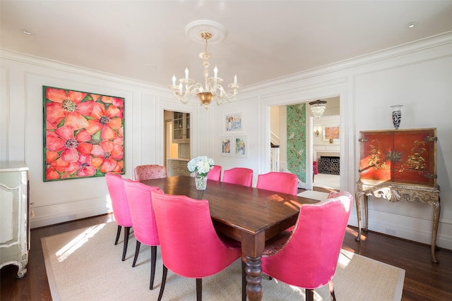 dining space featuring crown molding, dark hardwood / wood-style floors, a fireplace, and an inviting chandelier