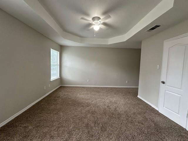 carpeted empty room with a raised ceiling