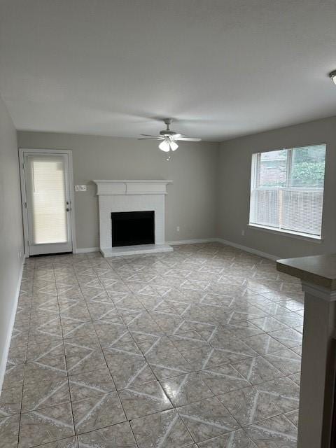 unfurnished living room with a brick fireplace and ceiling fan