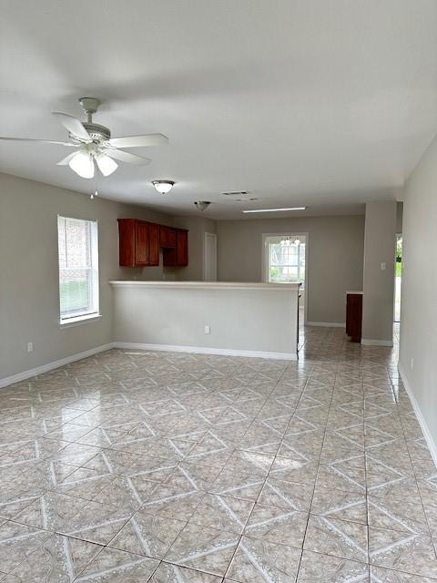 unfurnished room with ceiling fan and a healthy amount of sunlight