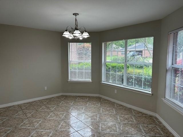 tiled spare room featuring an inviting chandelier