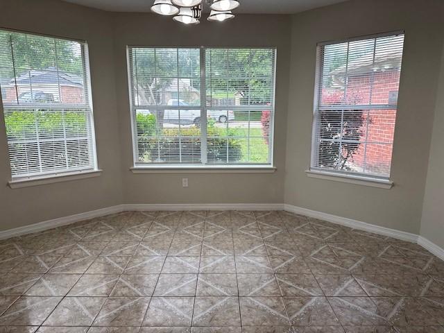 empty room with tile patterned flooring and an inviting chandelier