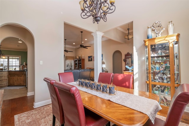 dining space featuring crown molding, ceiling fan with notable chandelier, decorative columns, and dark hardwood / wood-style floors