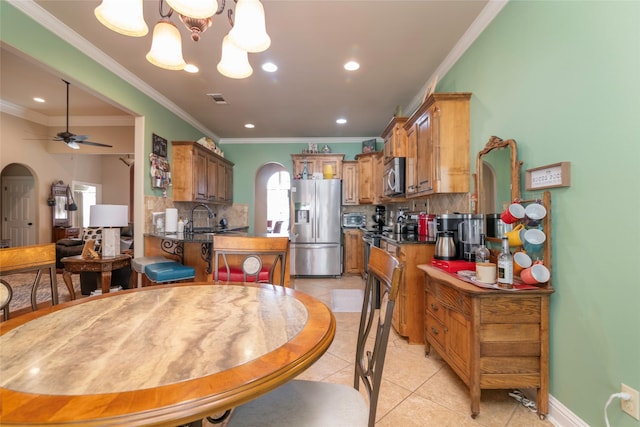 tiled dining room featuring sink, ceiling fan with notable chandelier, and ornamental molding