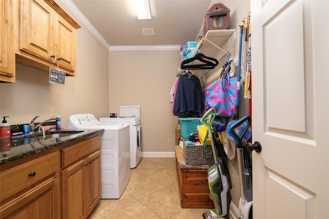 clothes washing area featuring sink, cabinets, ornamental molding, light tile patterned floors, and washing machine and dryer