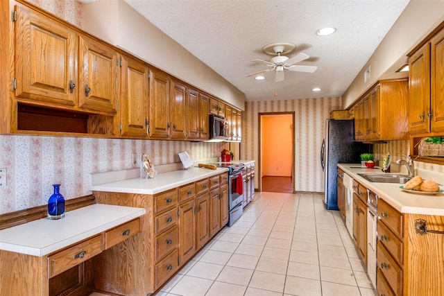 kitchen featuring sink, light tile patterned floors, ceiling fan, appliances with stainless steel finishes, and a textured ceiling