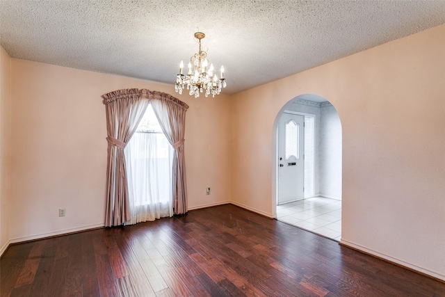 spare room featuring hardwood / wood-style flooring, a textured ceiling, and a notable chandelier