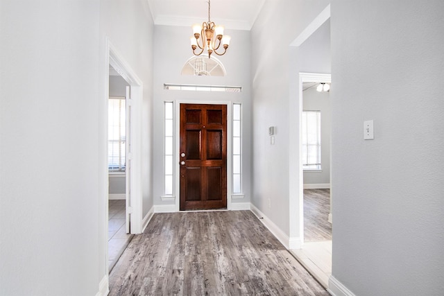 foyer featuring hardwood / wood-style flooring, a wealth of natural light, ornamental molding, and a chandelier