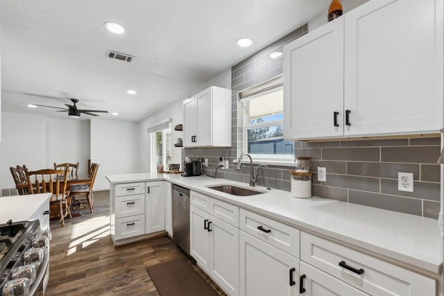 kitchen with dark wood-type flooring, sink, white cabinetry, kitchen peninsula, and stainless steel appliances