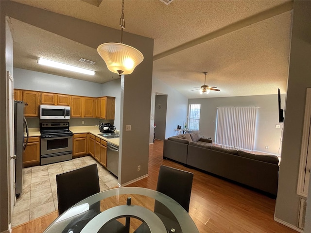 kitchen with sink, decorative light fixtures, vaulted ceiling, stainless steel appliances, and light hardwood / wood-style floors