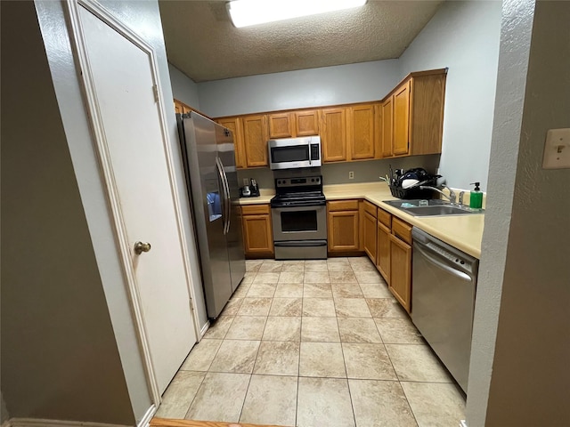 kitchen featuring stainless steel appliances, sink, a textured ceiling, and light tile patterned floors