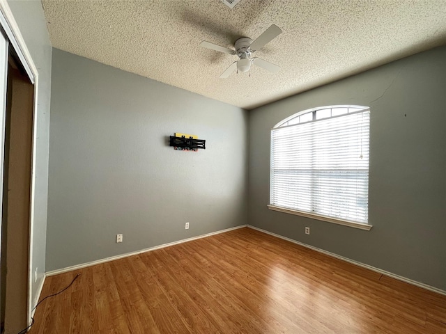 empty room featuring a textured ceiling, wood-type flooring, and ceiling fan