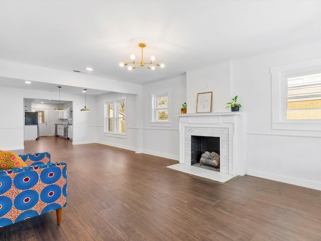 unfurnished living room with dark hardwood / wood-style floors, a fireplace, and an inviting chandelier