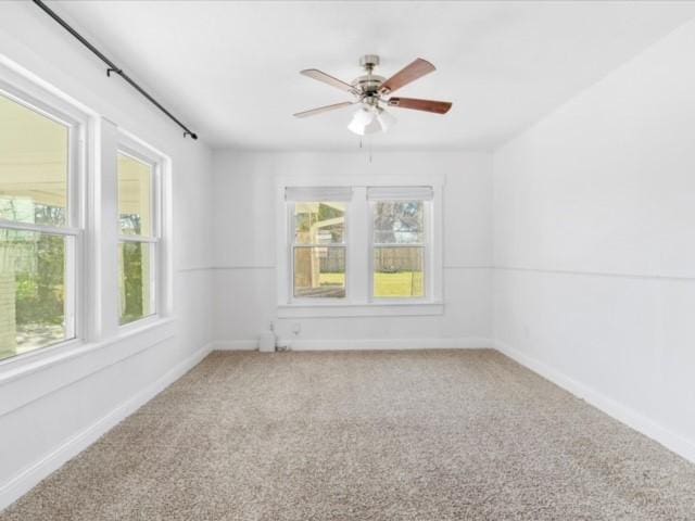 carpeted empty room featuring ceiling fan and a wealth of natural light